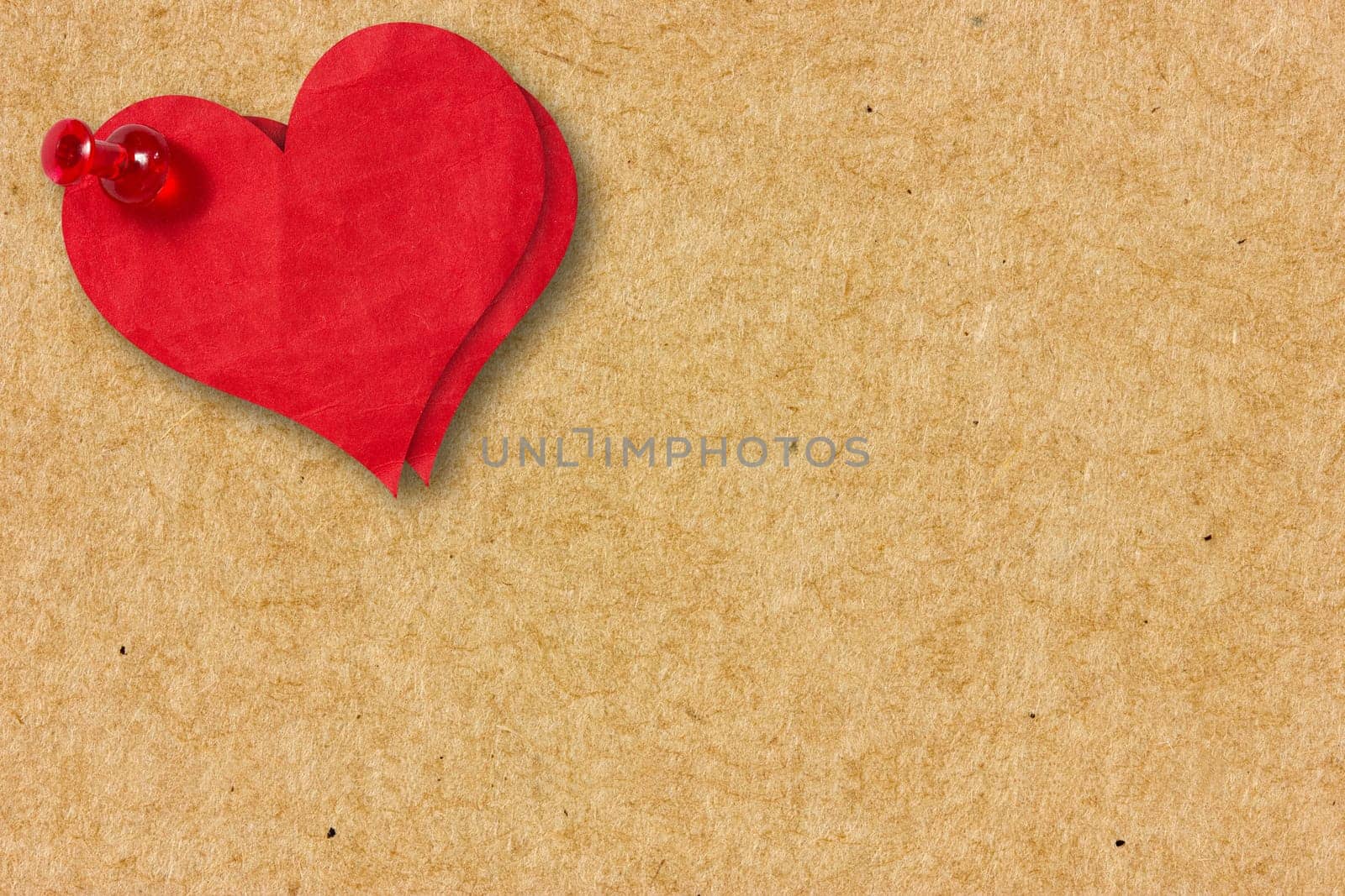 Two red paper hearts pinned to the  cardboard