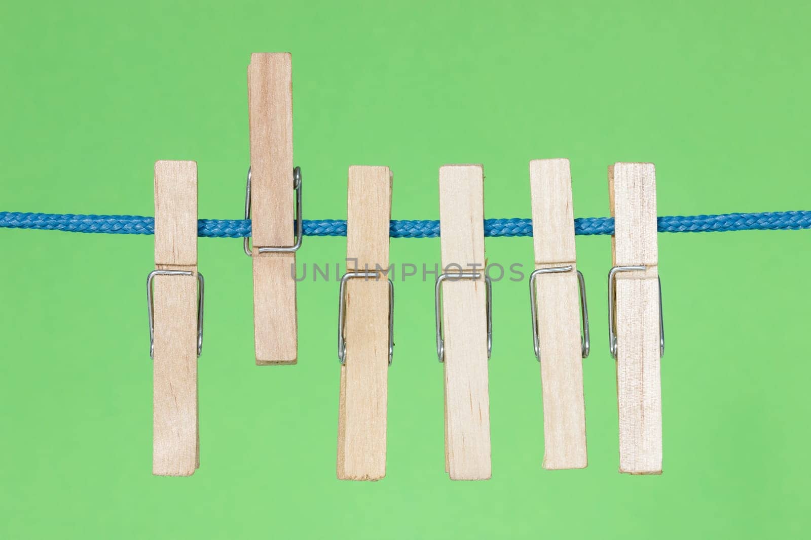 Wooden clothes pegs hang on the green background
