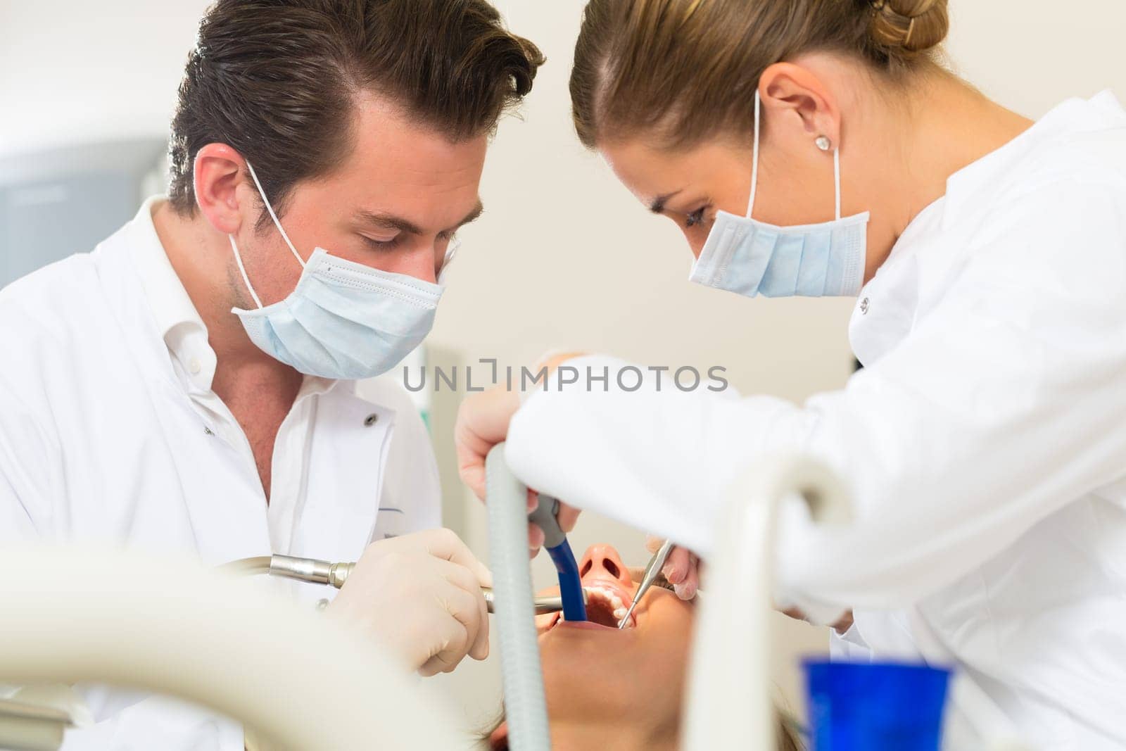 Female patient with dentist and dental assistant during treatment