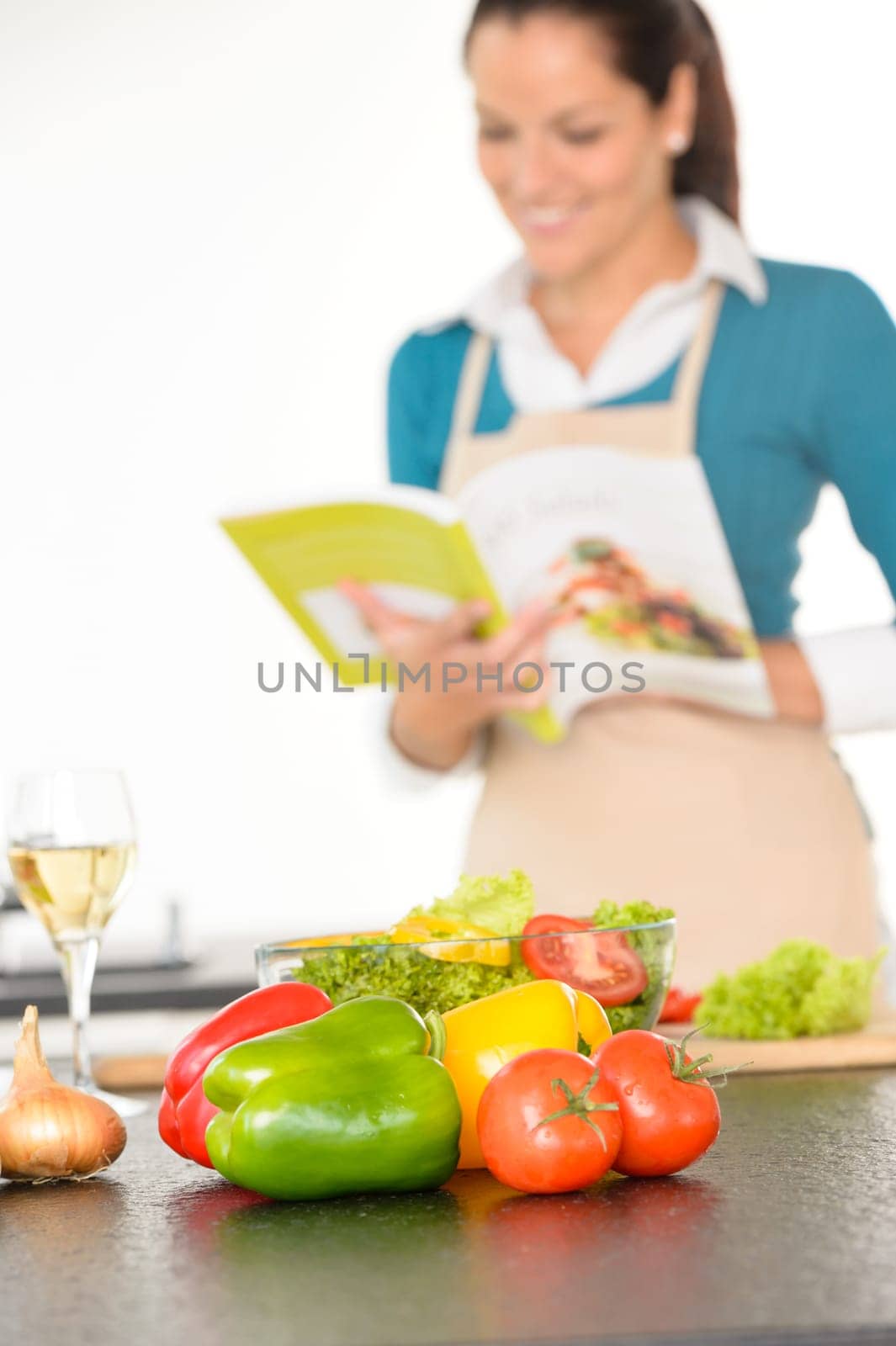 Happy woman preparing recipe vegetables wine kitchen cooking book