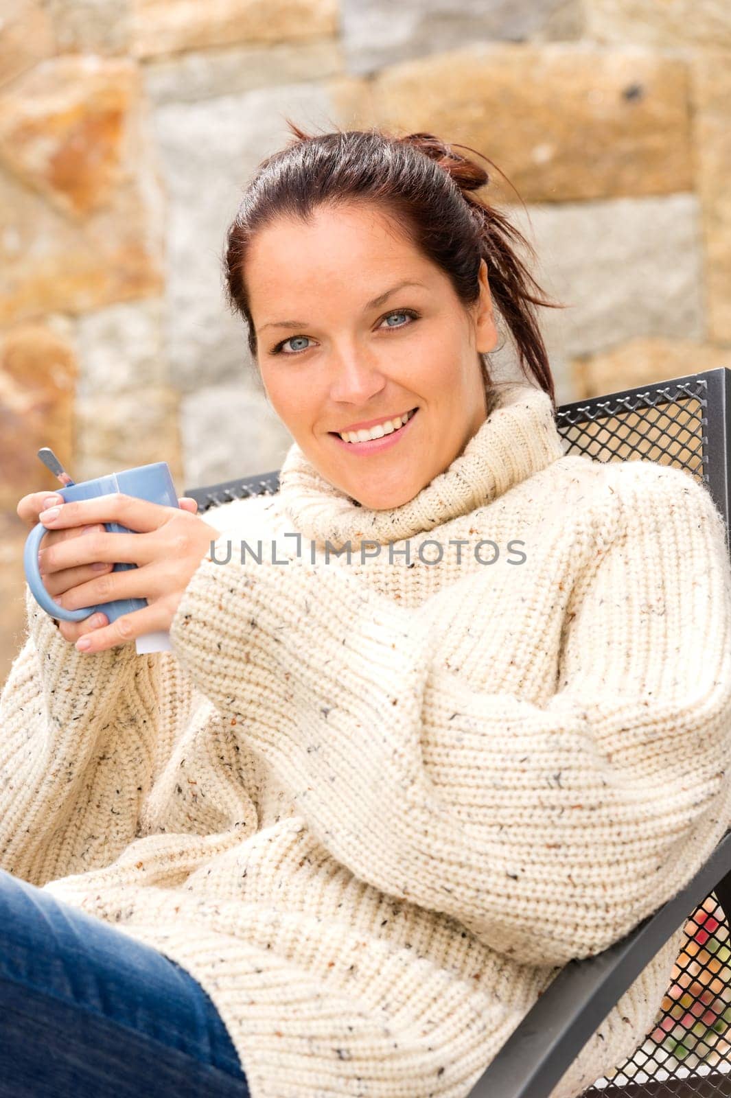 Smiling woman drinking hot cocoa sitting relaxing garden knitted sweater