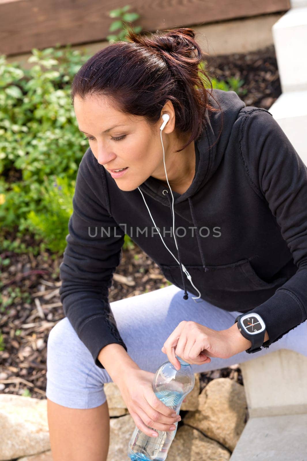 Tired woman relaxing after running sport bottle headphones sweatsuit
