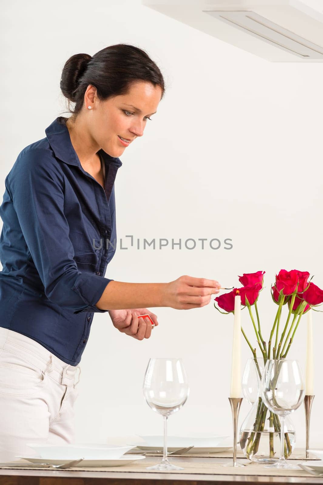 Woman lighting candle dining room Valentine's day red roses dinner