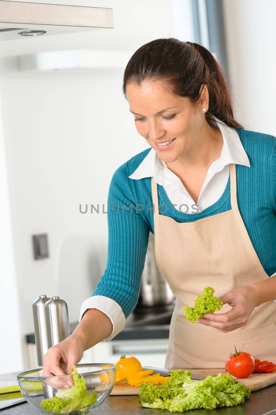 Smiling young woman making salad vegetables preparing meal kitchen