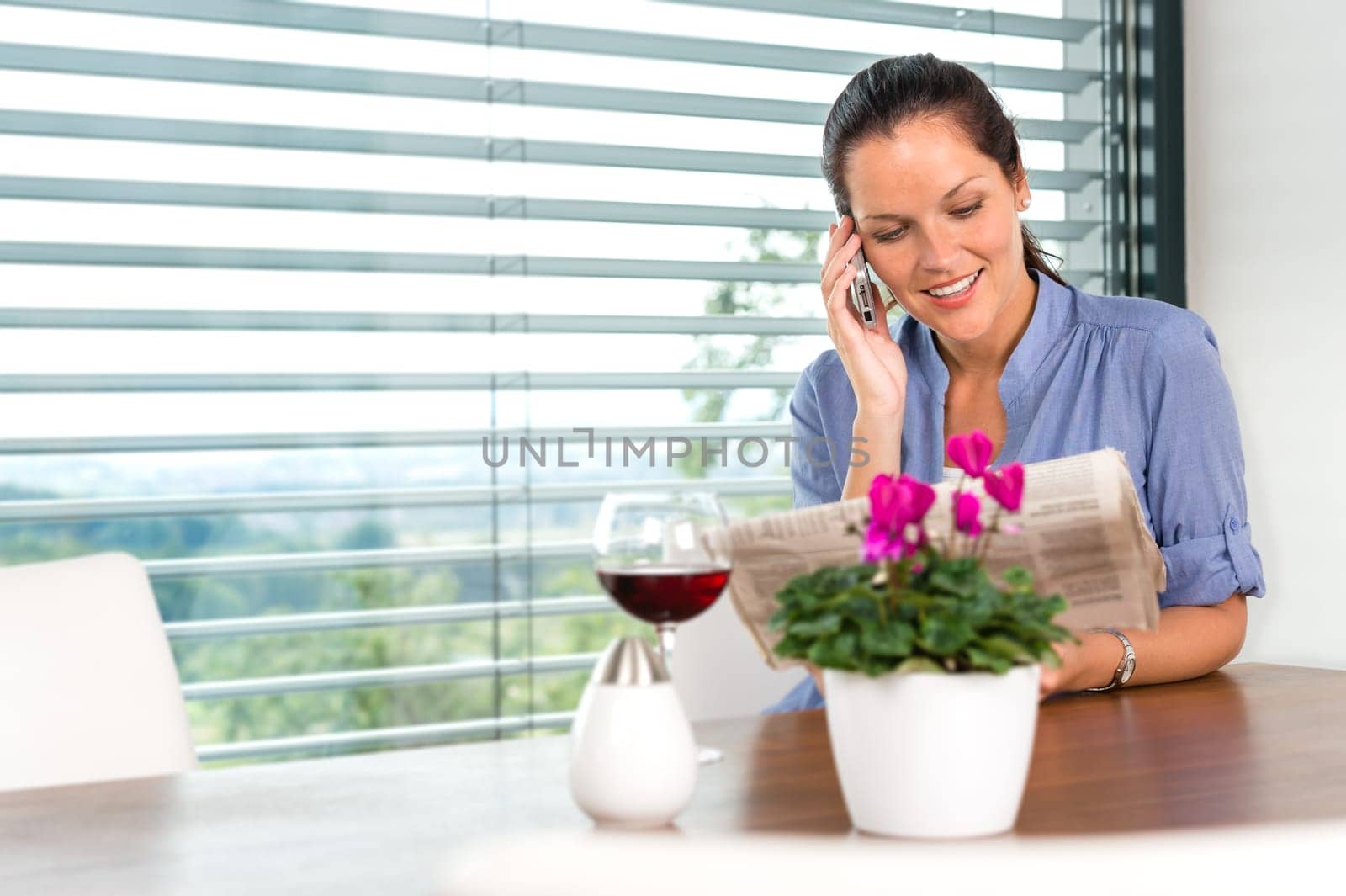 Smiling woman talking mobile phone relaxing reading home living room