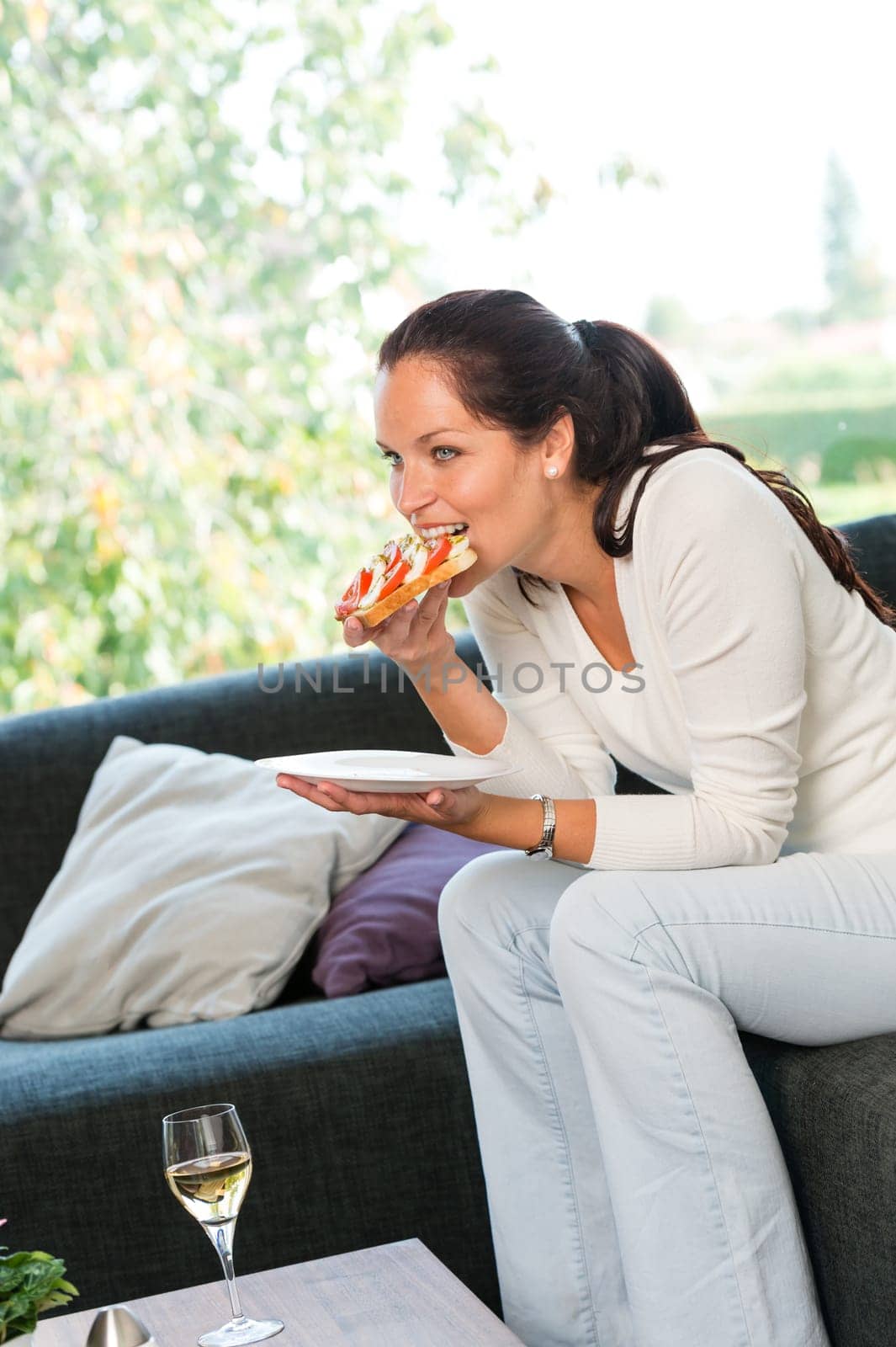 Woman eating sandwich lunch breakfast home sofa couch white wine