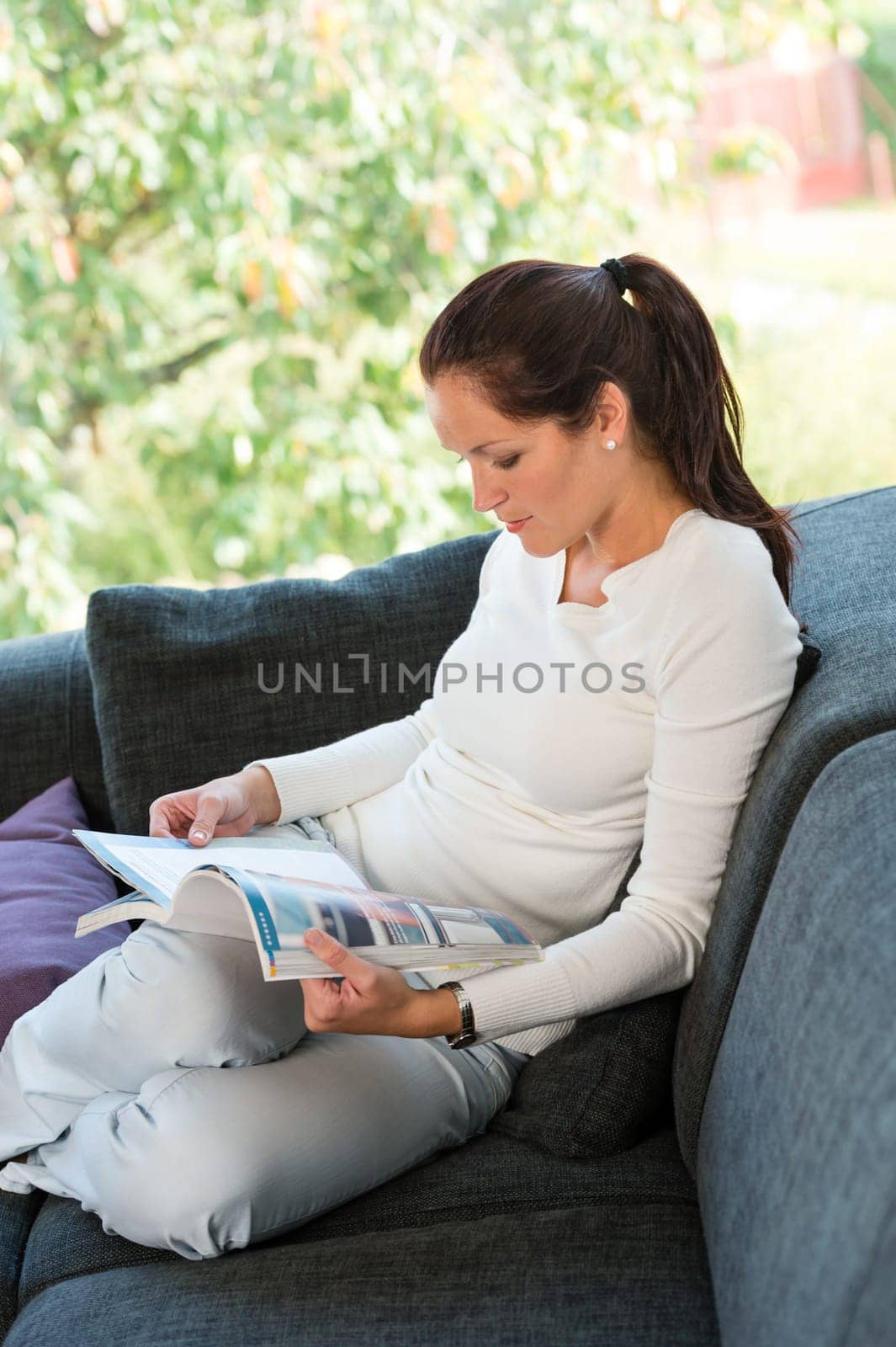 Young woman reading magazine living room couch sofa