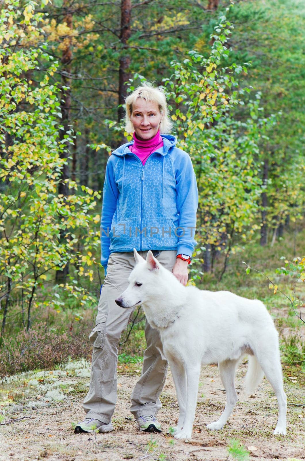 The woman with a dog walk in an autumn wood