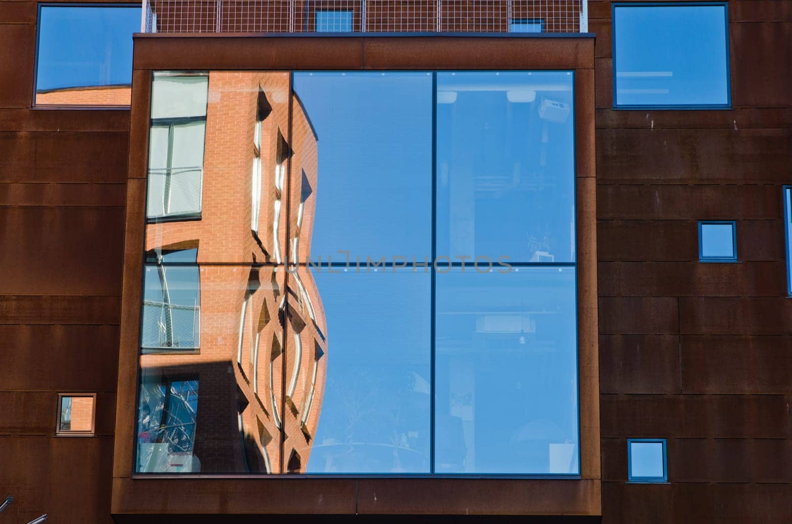 houses and blue sky reflected in windows of modern office building.