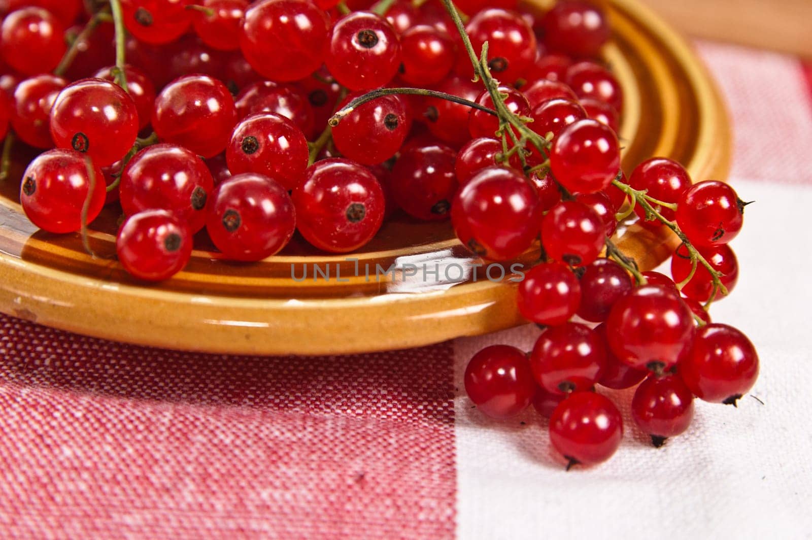Berries of a red currant in a plate on a table