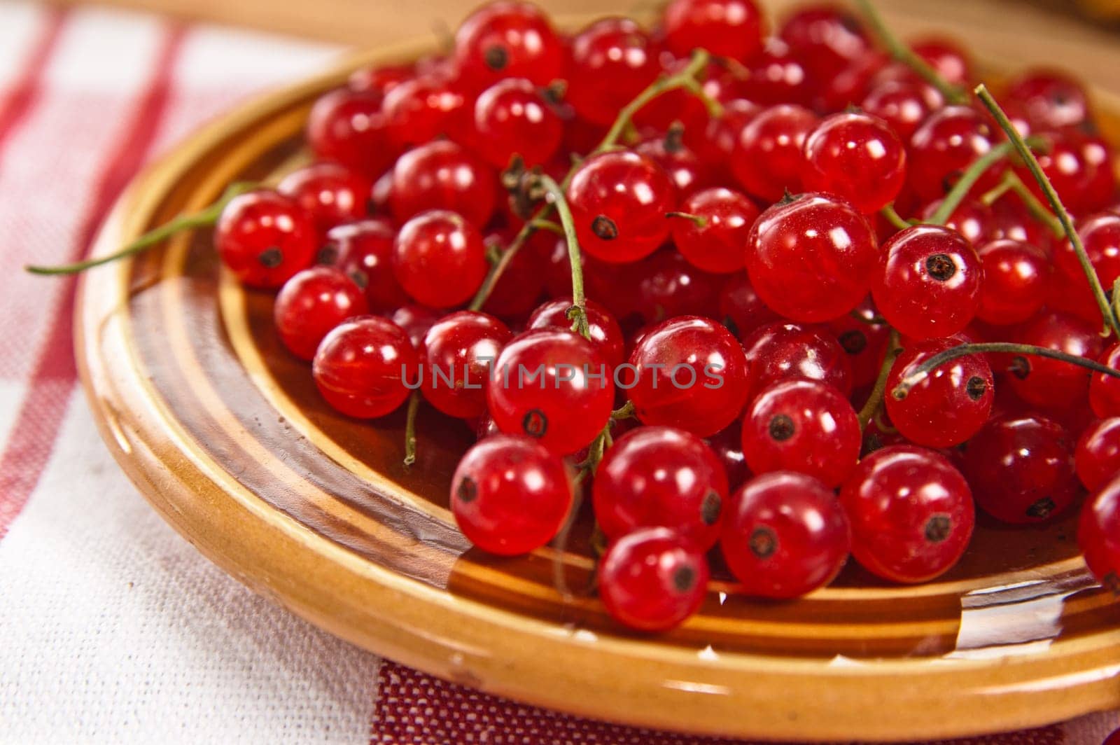 Berries of a red currant in a plate on a table