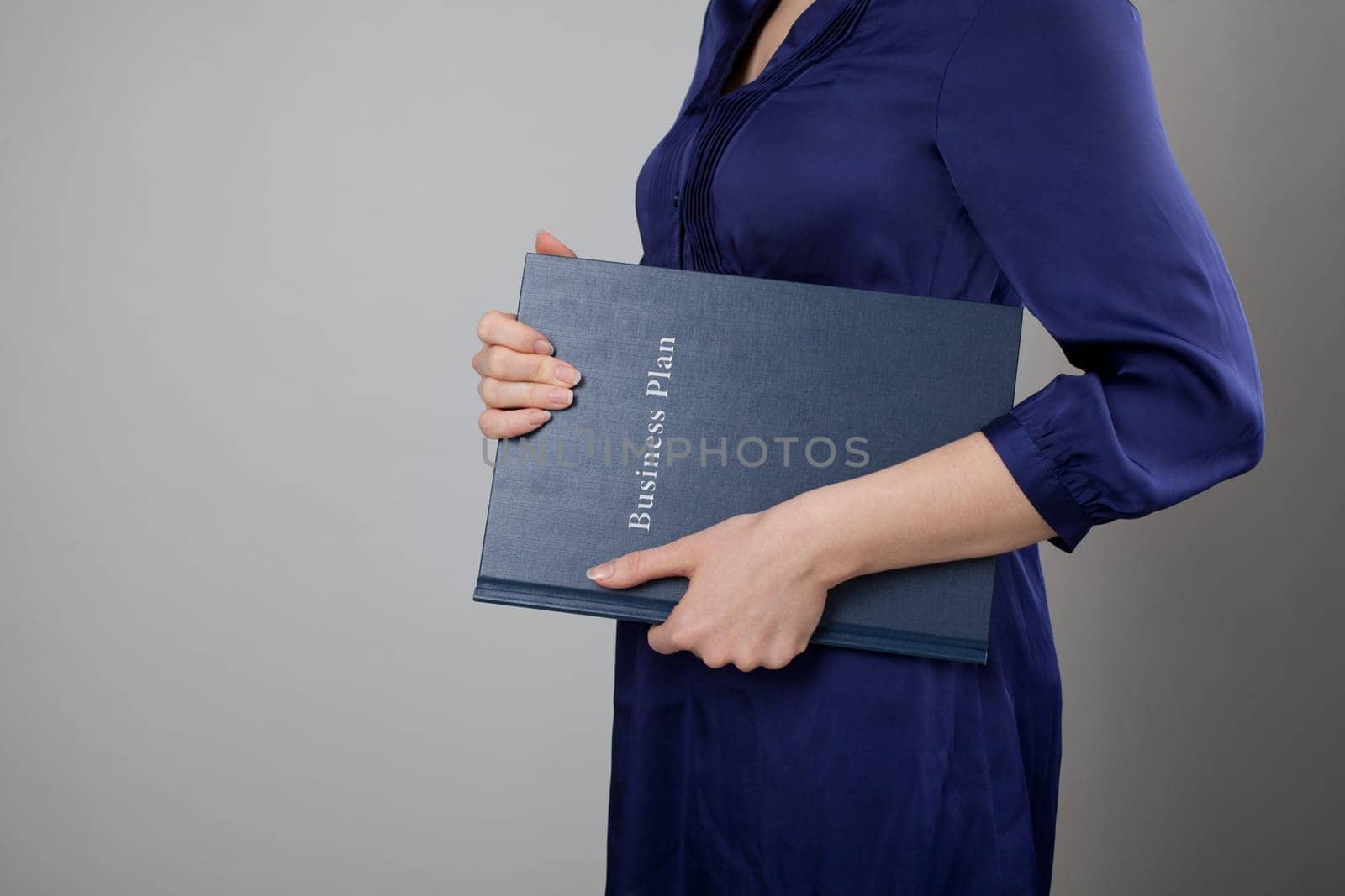 Woman holding business plan. Gray background.
