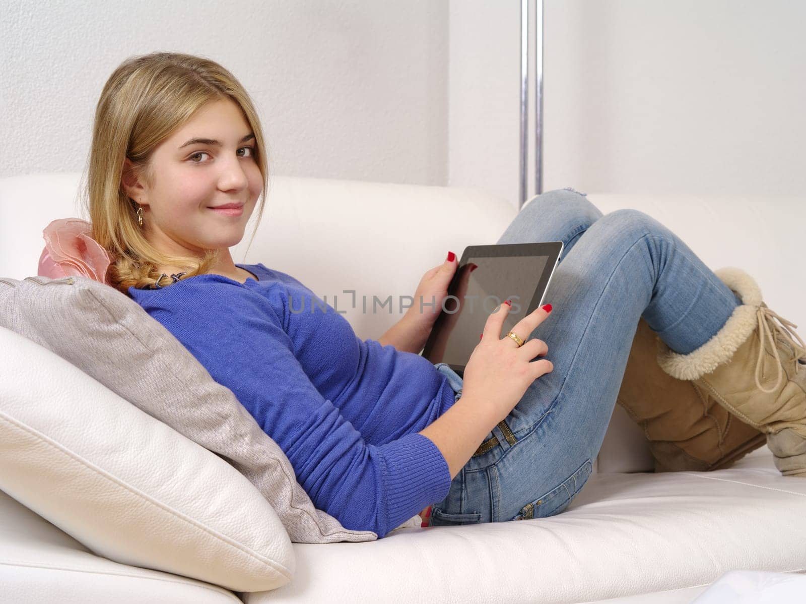 Photo of a happy young teenage female using a computer tablet at home.