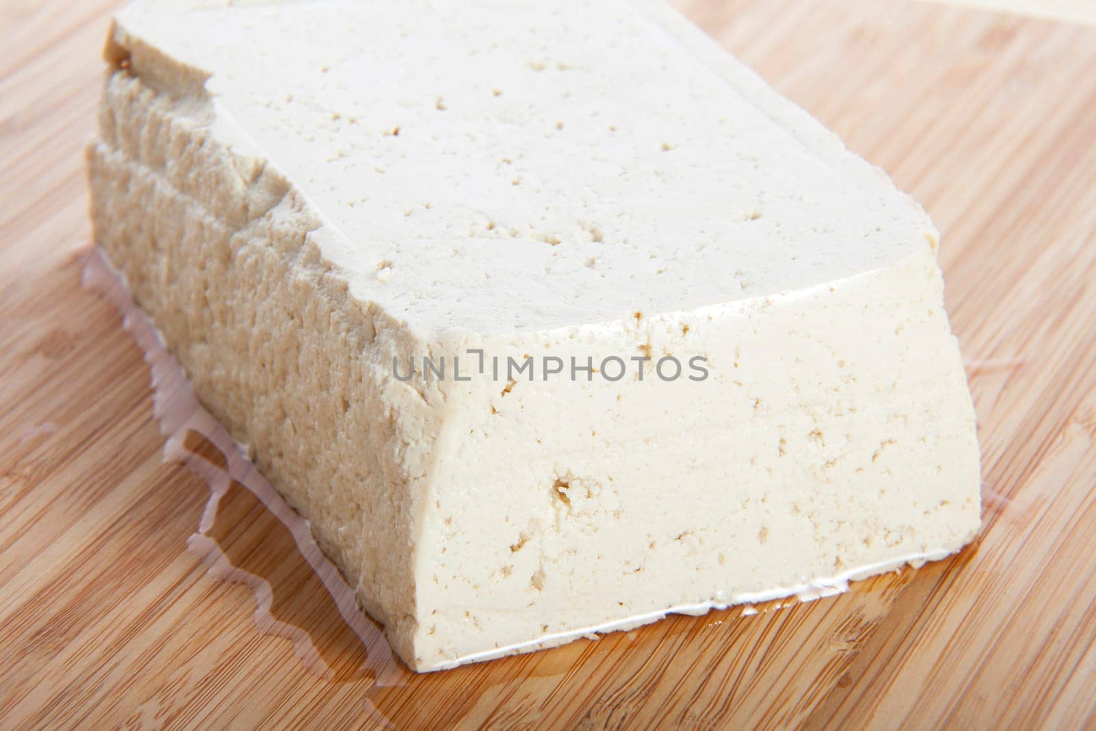 Block of fresh tofu on cutting block.