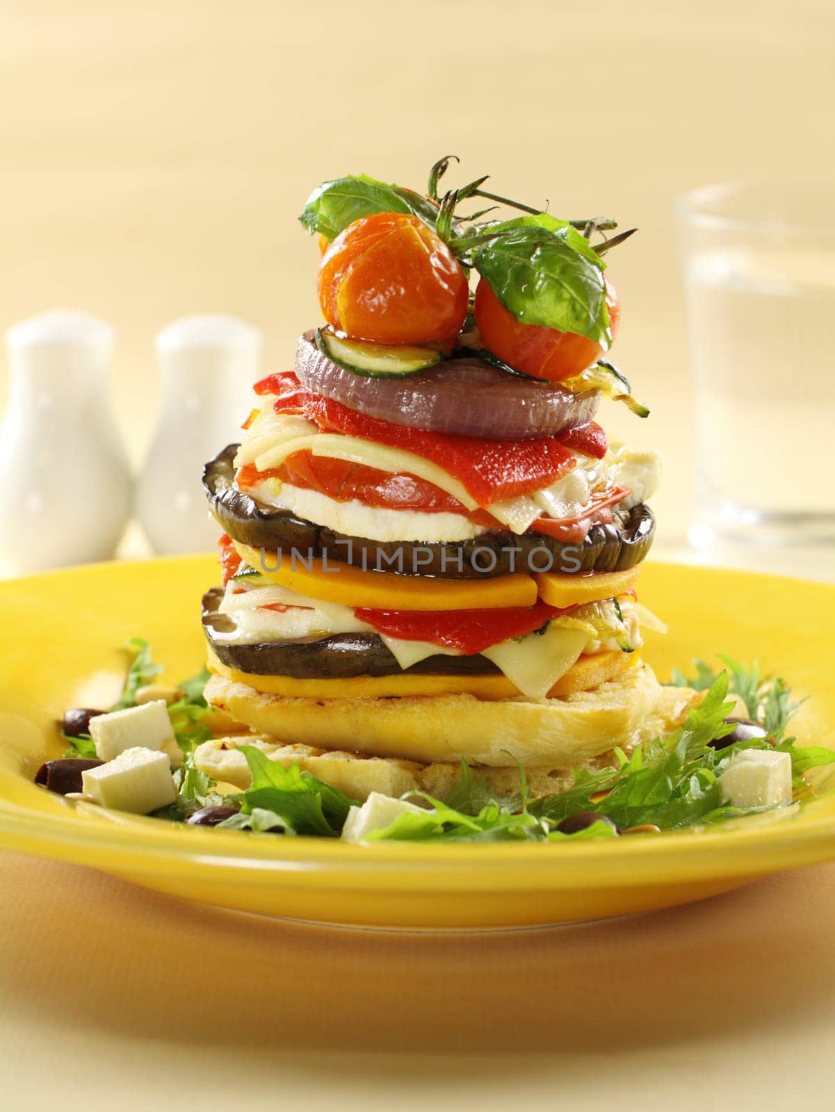 Assorted vegetables including cherry tomato, eggplant, onion and pumpkin stacked on turkish bread.