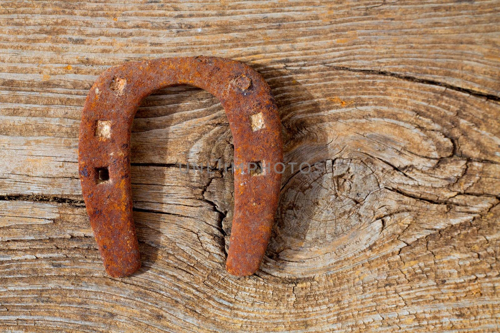 Antique horseshoe luck symbol rusted on vintage wood background