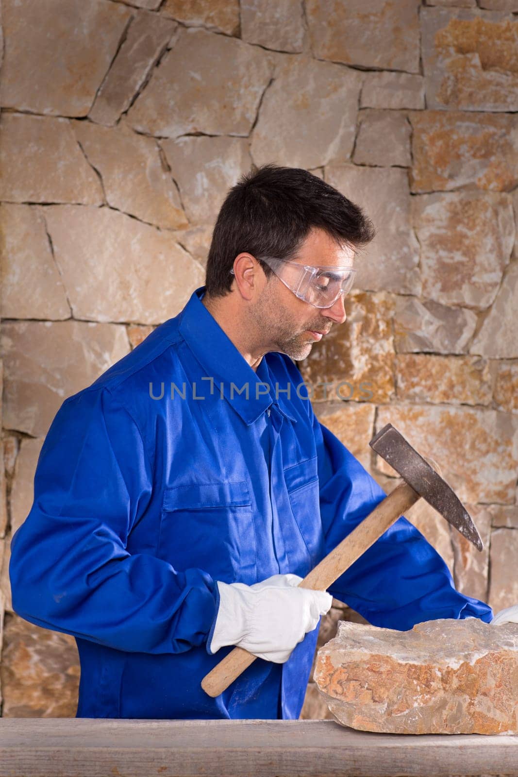 Masonry mason stonecutter man with hammer working on stone wall construction