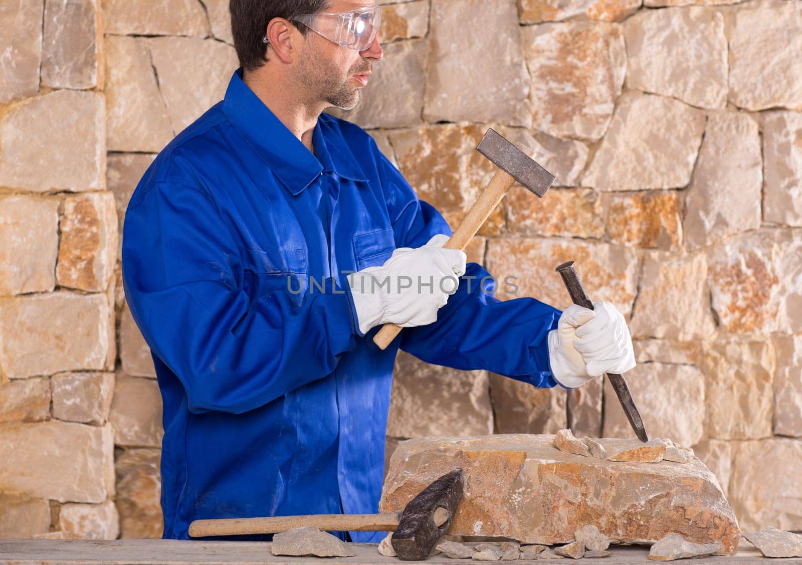 Masonry mason stonecutter man with hammer working on stone wall construction