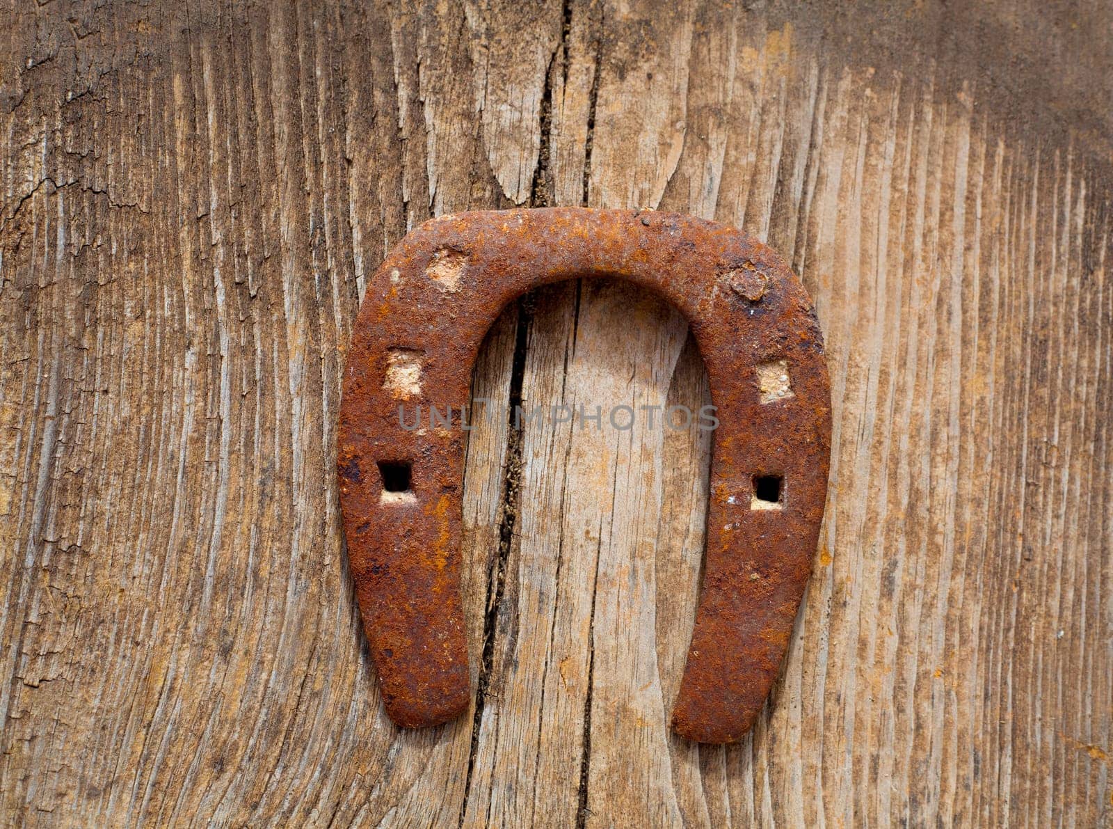 Antique horseshoe luck symbol rusted on vintage wood background