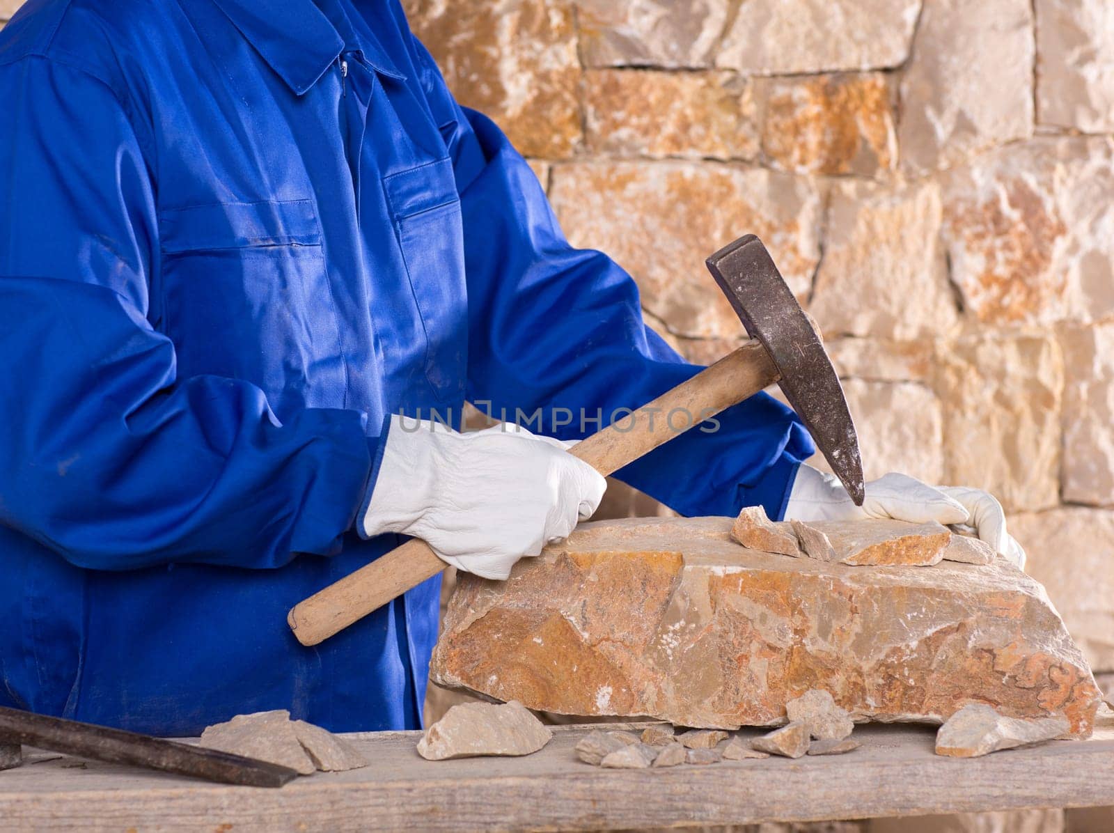 Masonry mason stonecutter man with hammer working on stone wall construction