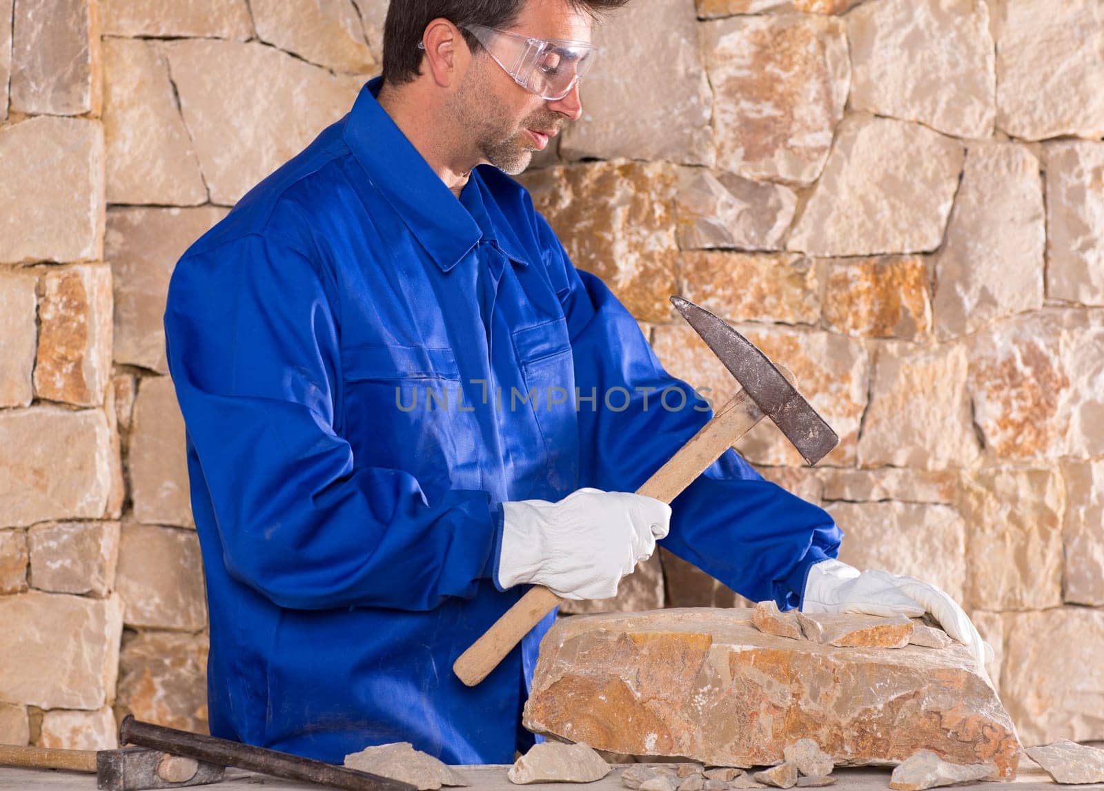 Masonry mason stonecutter man with hammer working on stone wall construction
