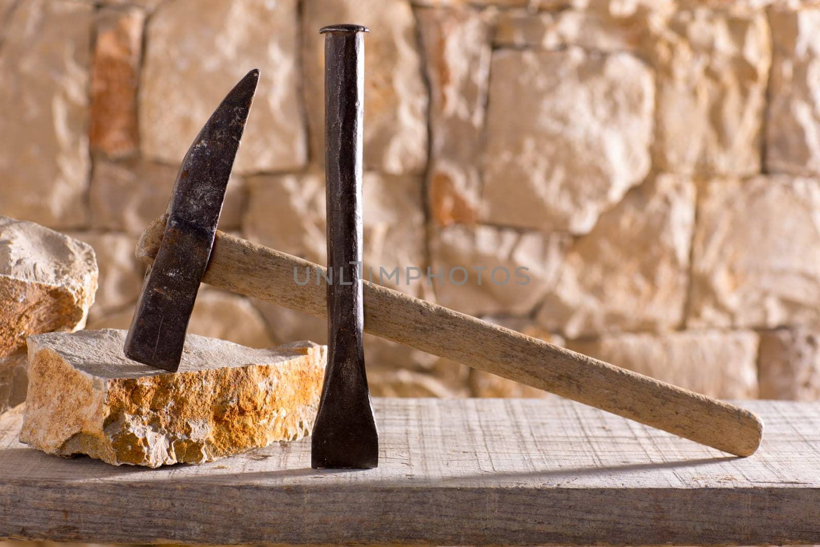 Hammer mason tools of stonecutter masonry work in a contruction stone wall