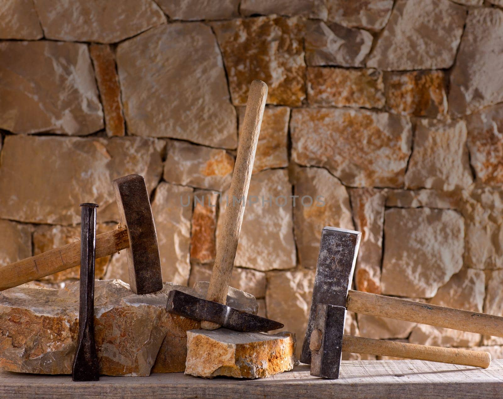 Hammer mason tools of stonecutter masonry work in a contruction stone wall