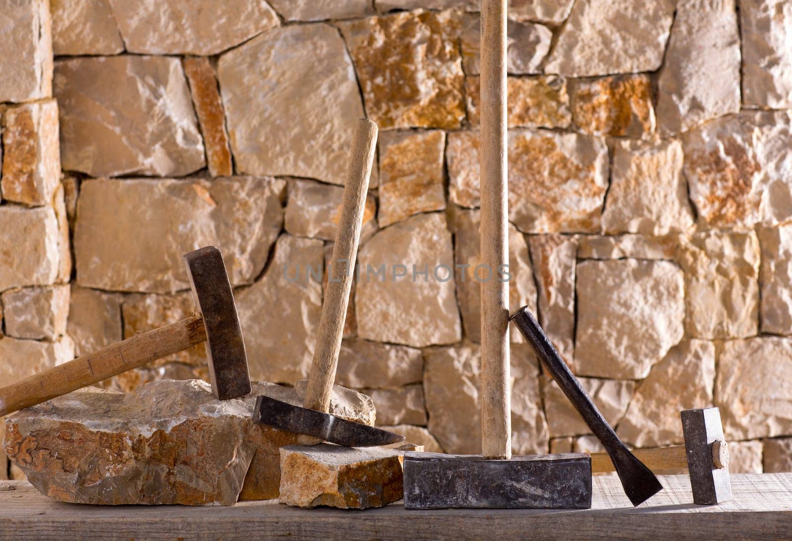 Hammer mason tools of stonecutter masonry work in a contruction stone wall