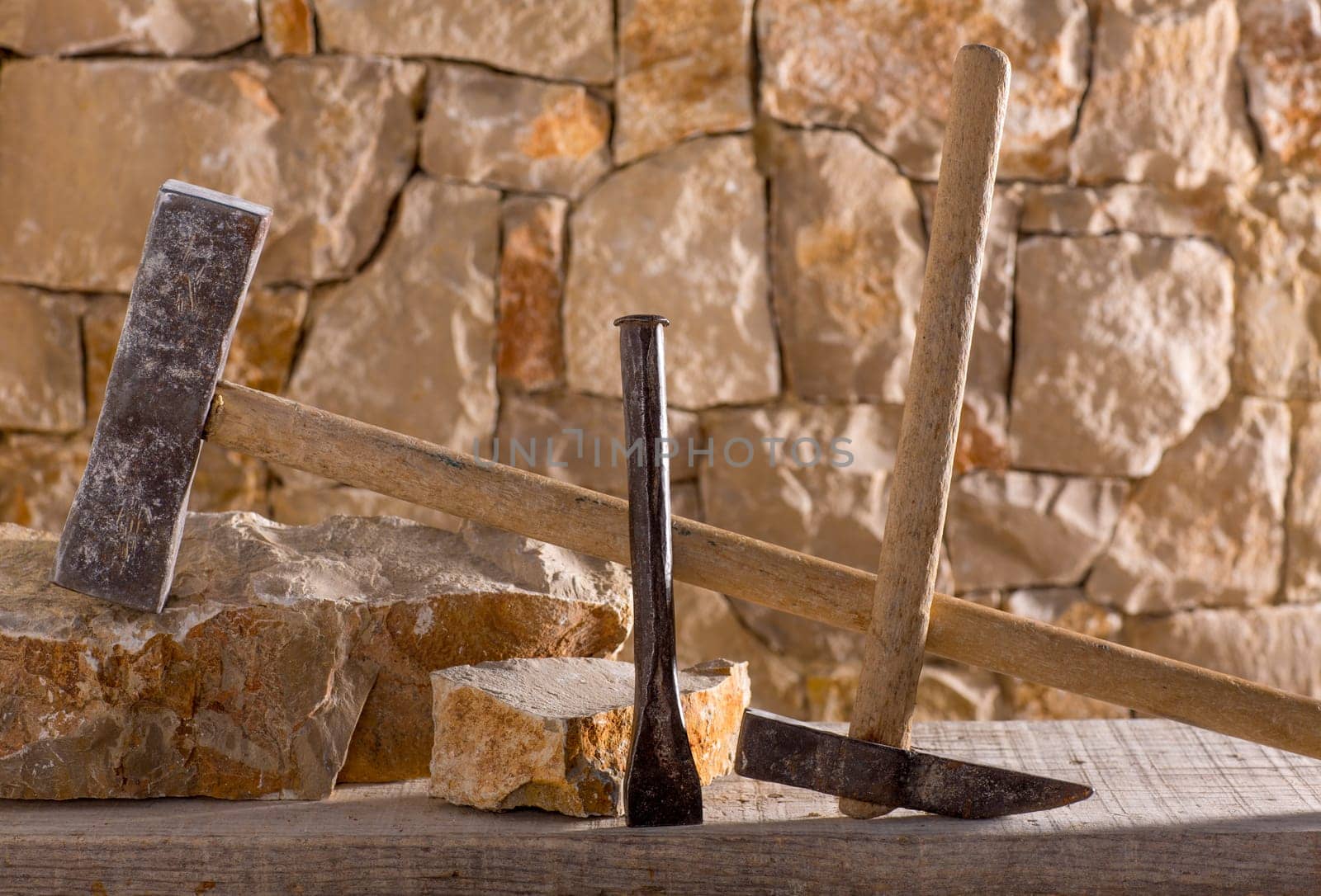 Hammer mason tools of stonecutter masonry work in a contruction stone wall