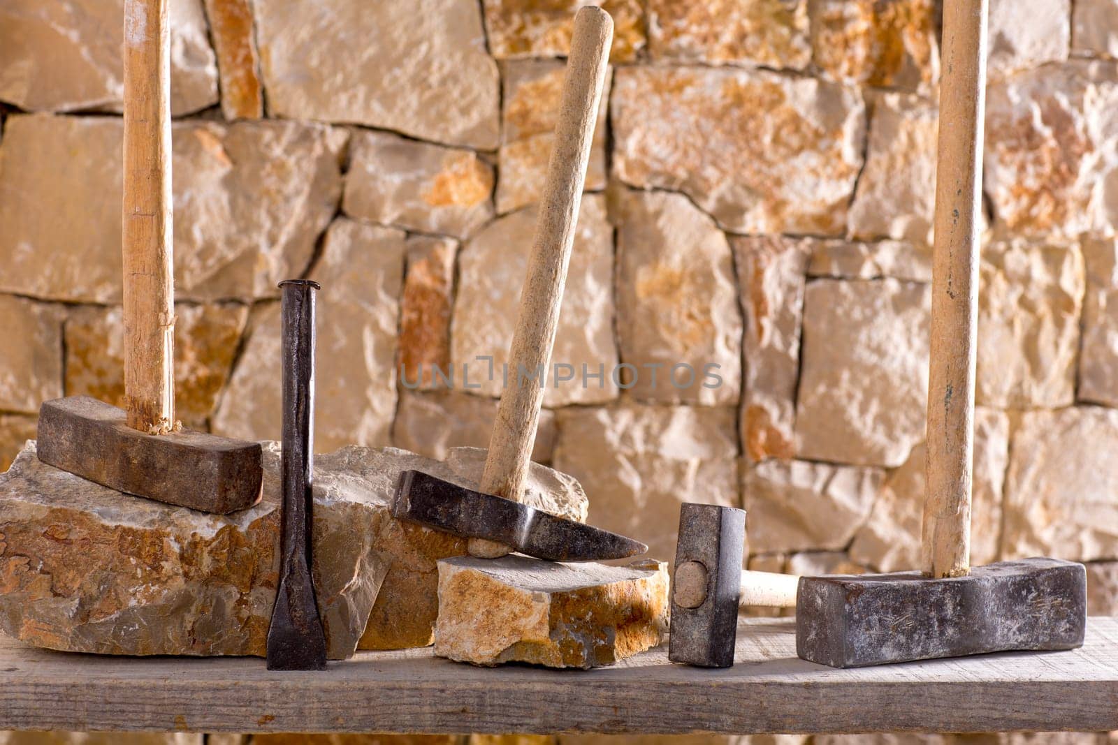 Hammer mason tools of stonecutter masonry work in a contruction stone wall