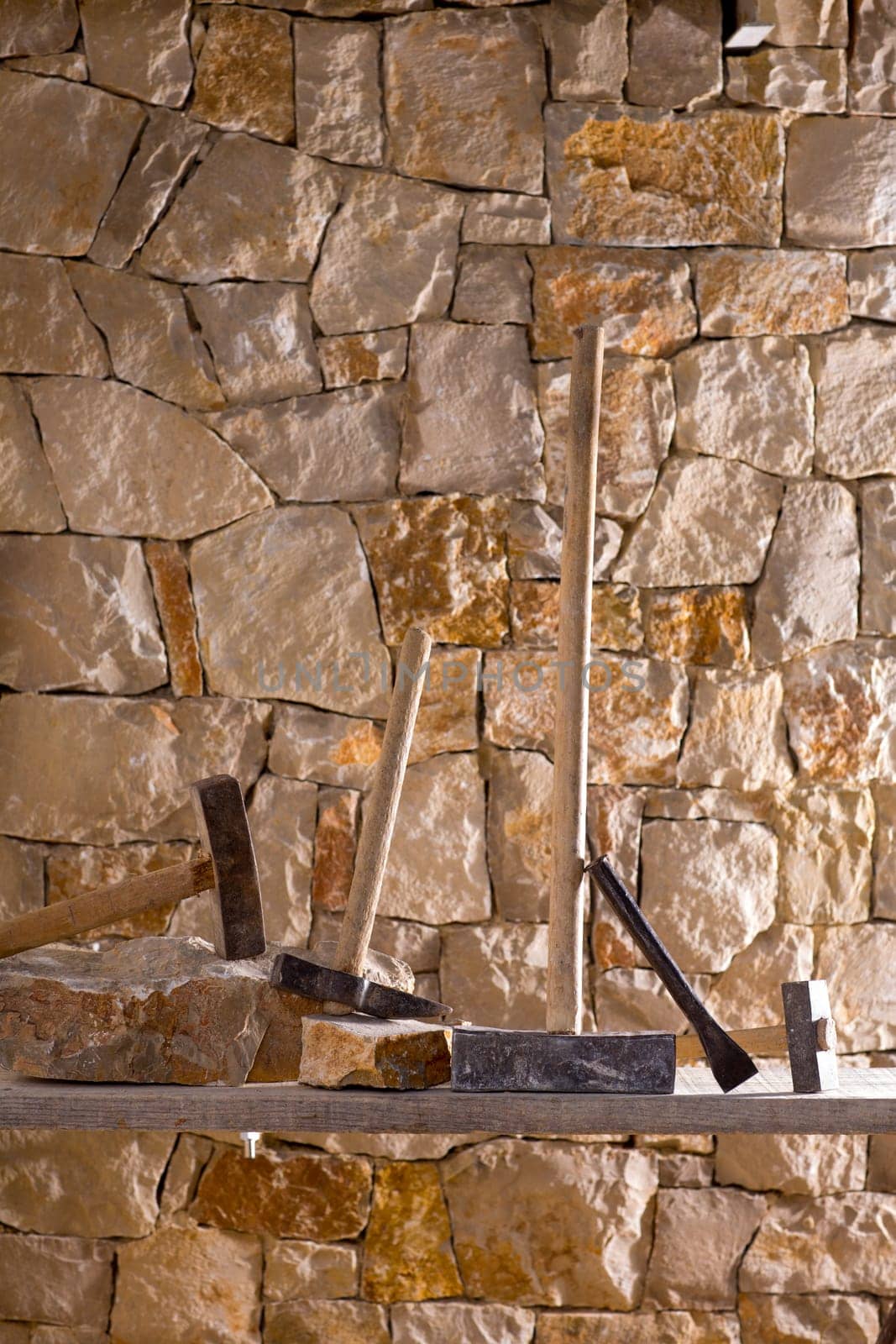 Hammer mason tools of stonecutter masonry work in a contruction stone wall