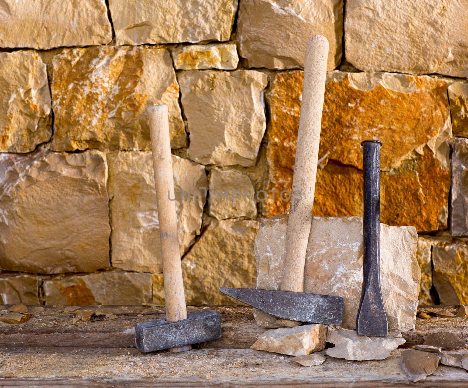 Hammer mason tools of stonecutter masonry work in a contruction stone wall