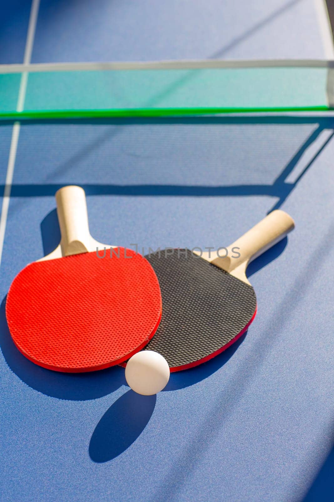 table tennis ping pong two paddles and white ball on blue board