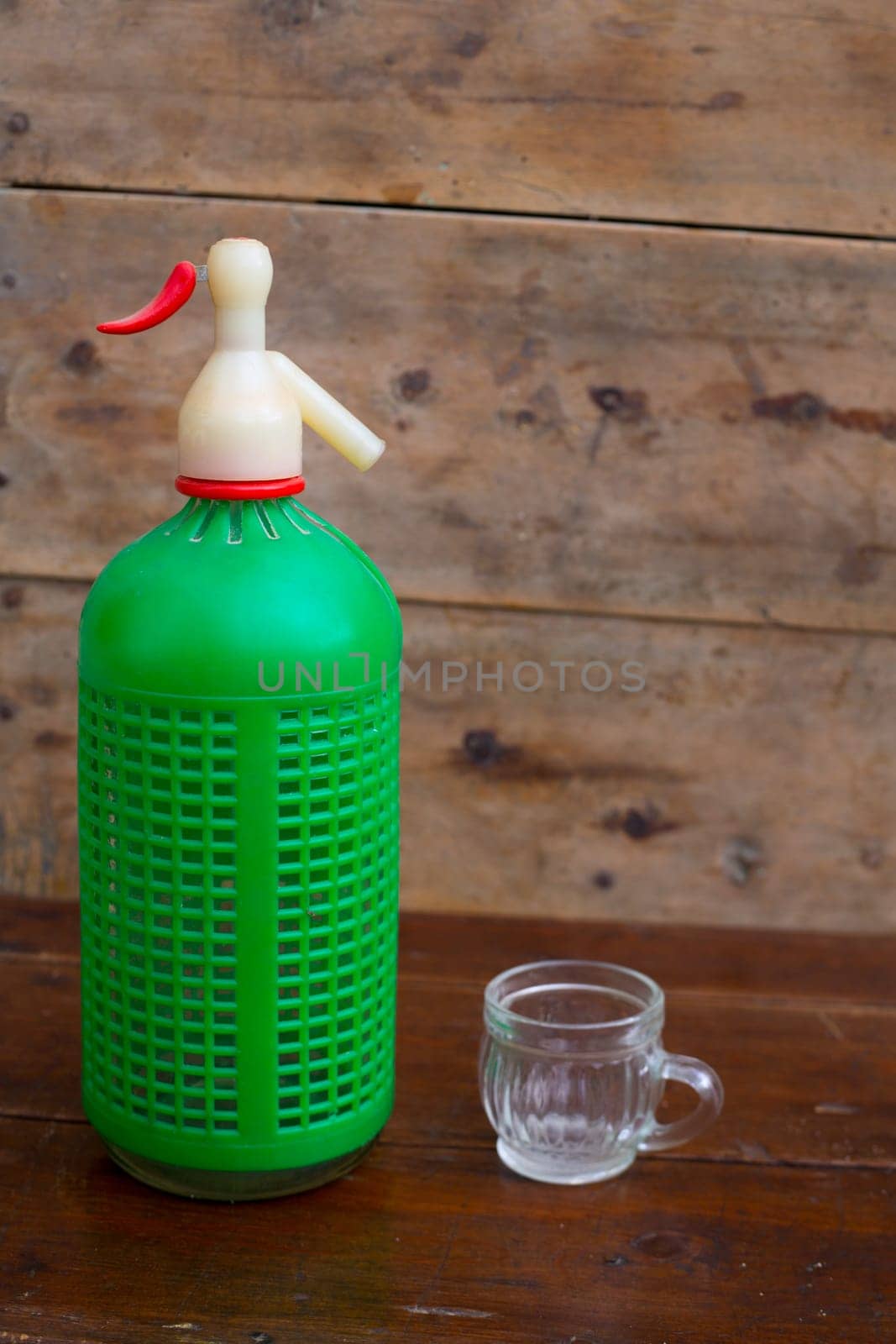 ancient soda bottle with little cup in wooden background