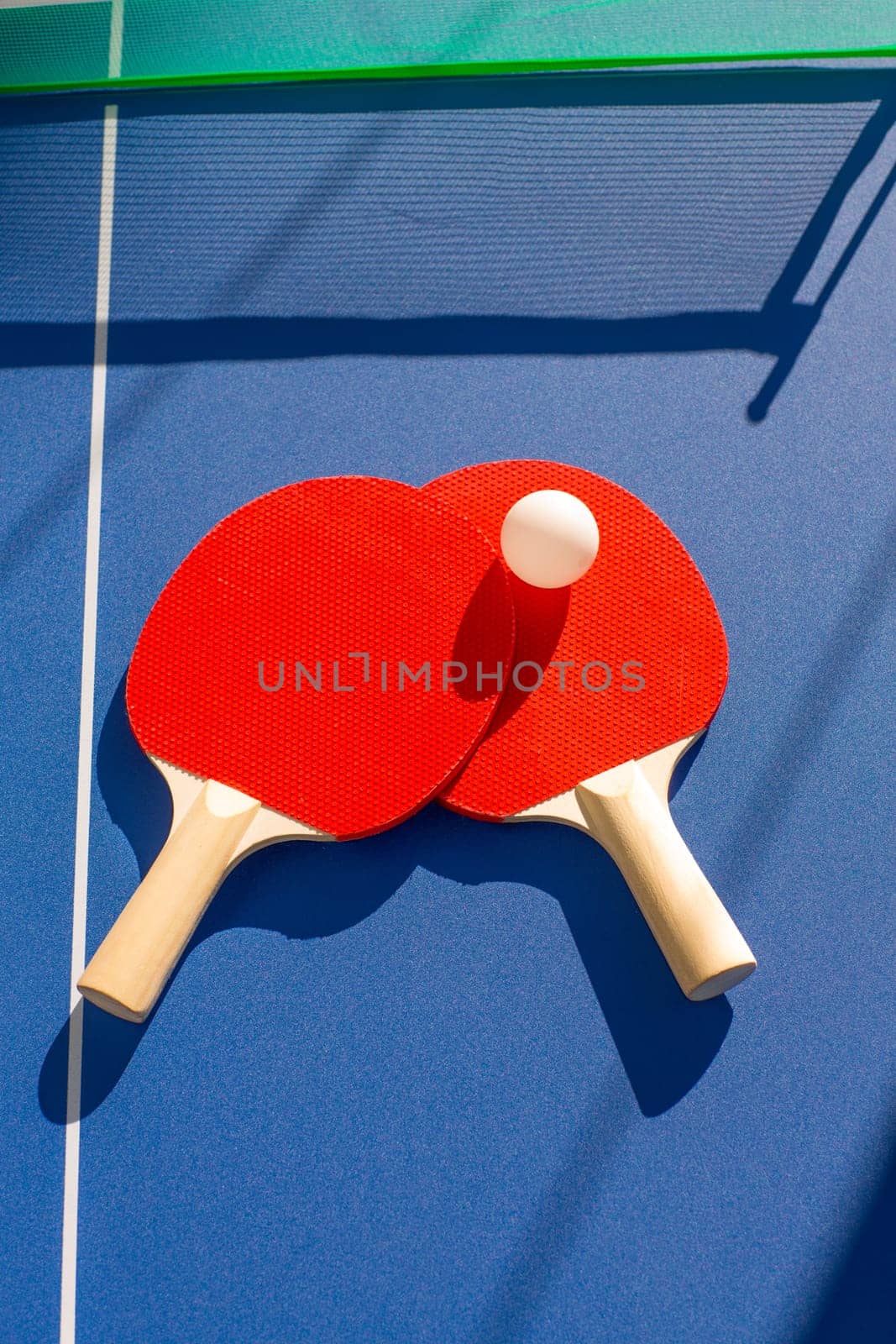 table tennis ping pong two paddles and white ball on blue board