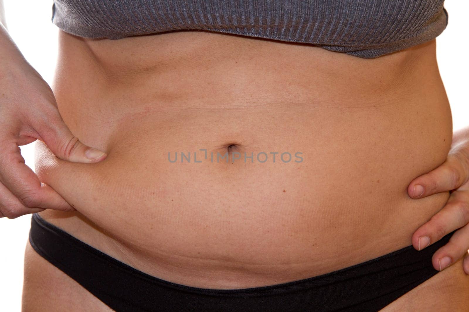 Woman's fingers measuring her belly fat