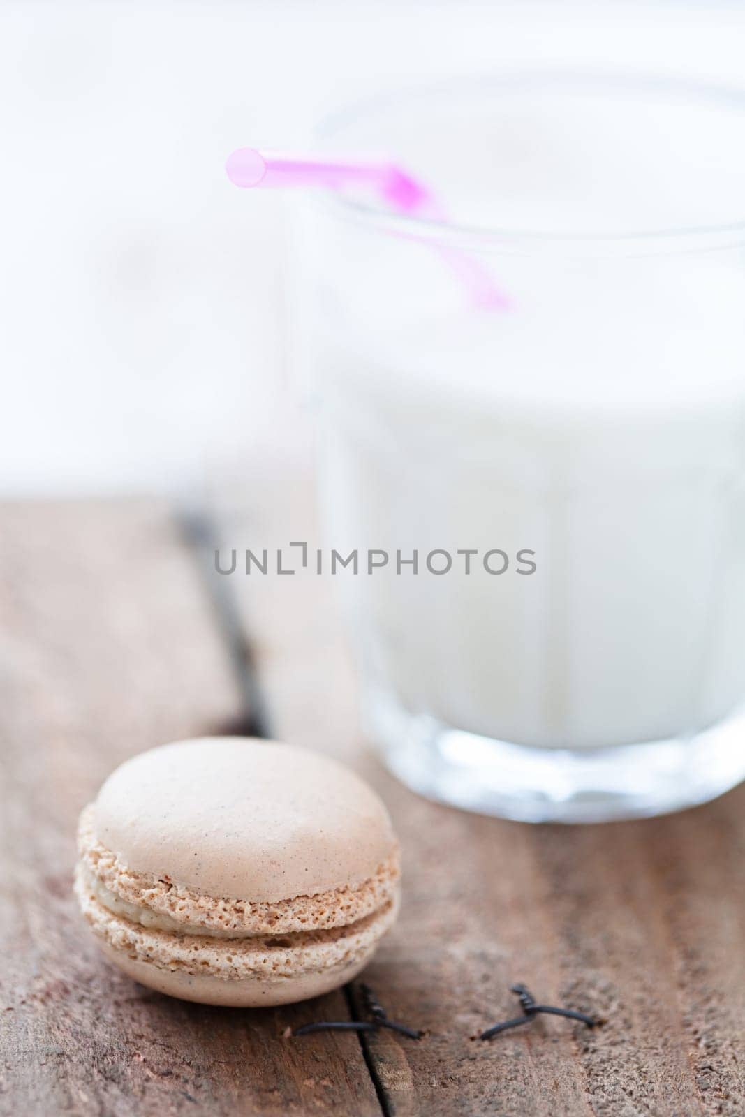 Closeup of macaroon and glass of milk on wooden table