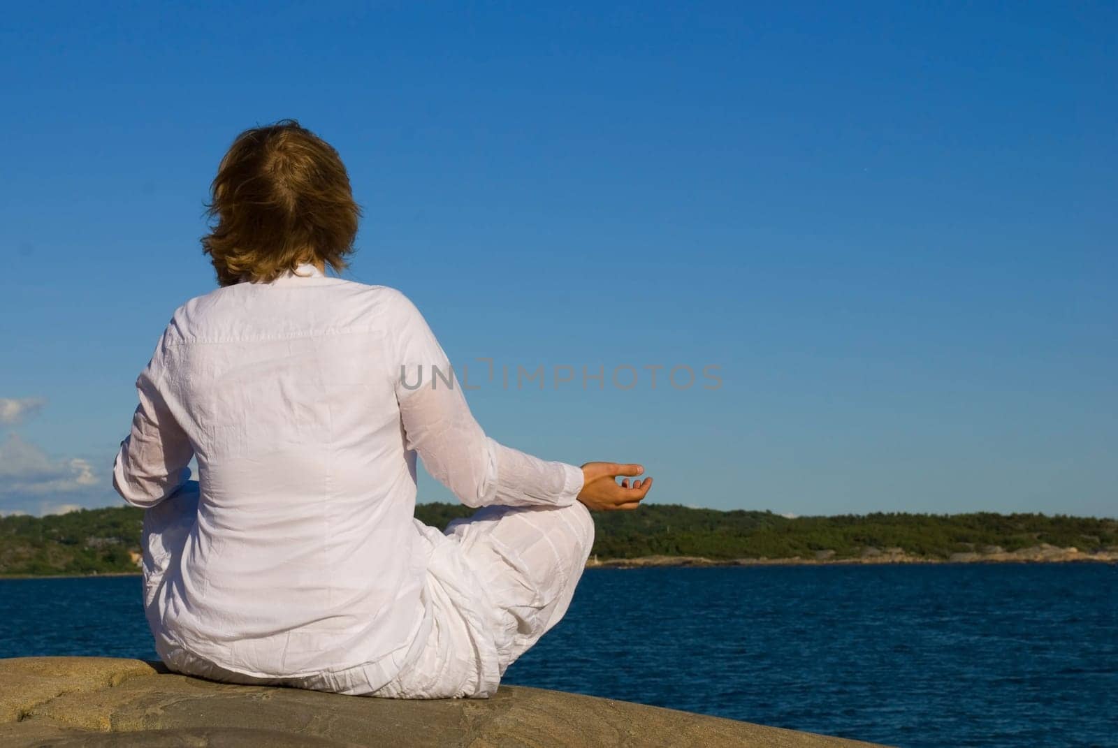 a woman in white cloth doing yoga in front of the ocean