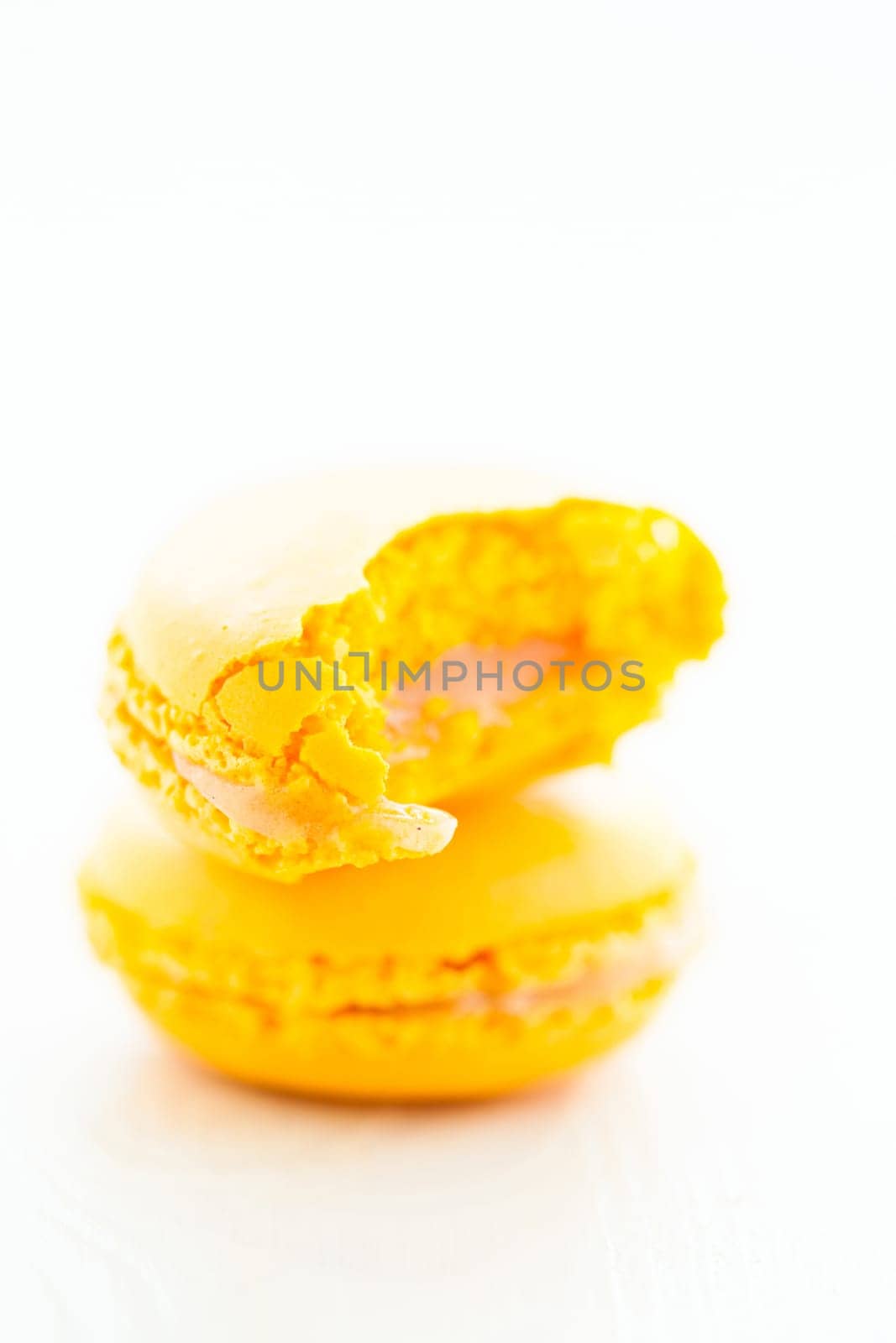 Closeup of one full and one half eaten yellow lemon macaroon