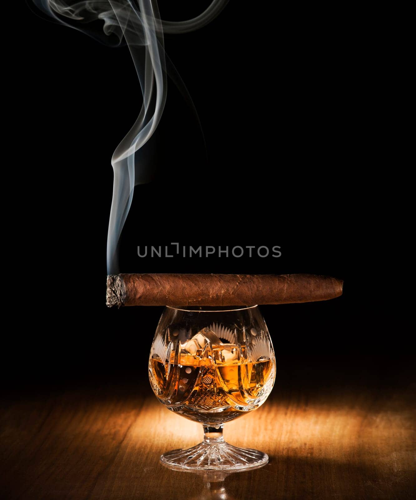 Cognac and cigar on wooden background close up