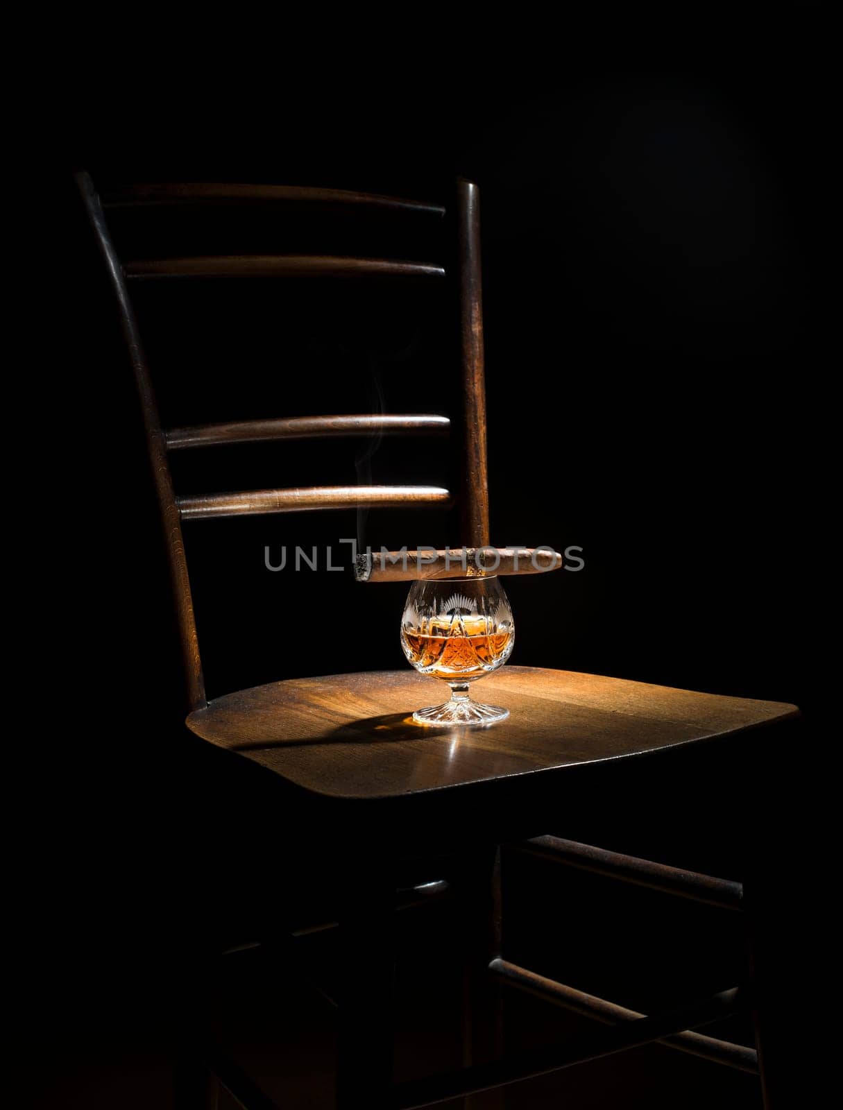 Cognac and cigar on wooden chair close up