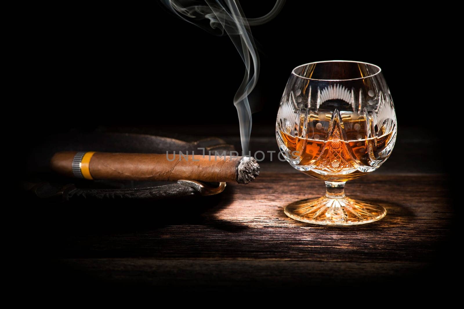Cognac and cigar on wooden background close up