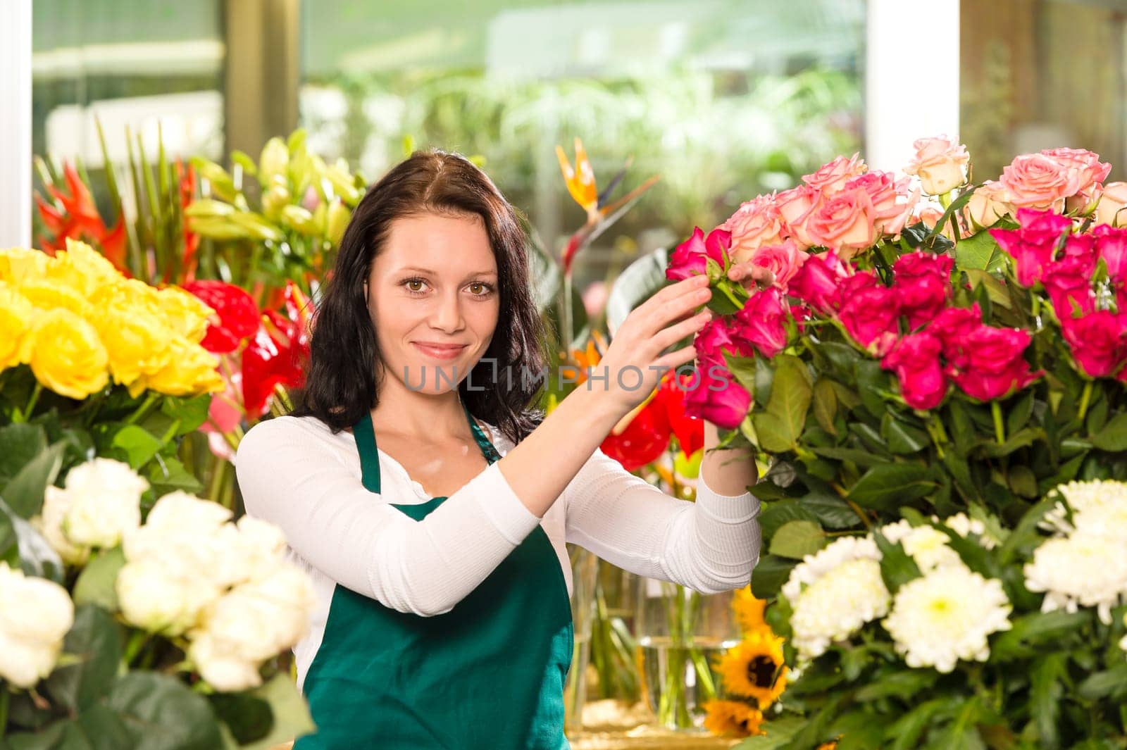 Happy young woman arranging flowers florist shop colorful roses