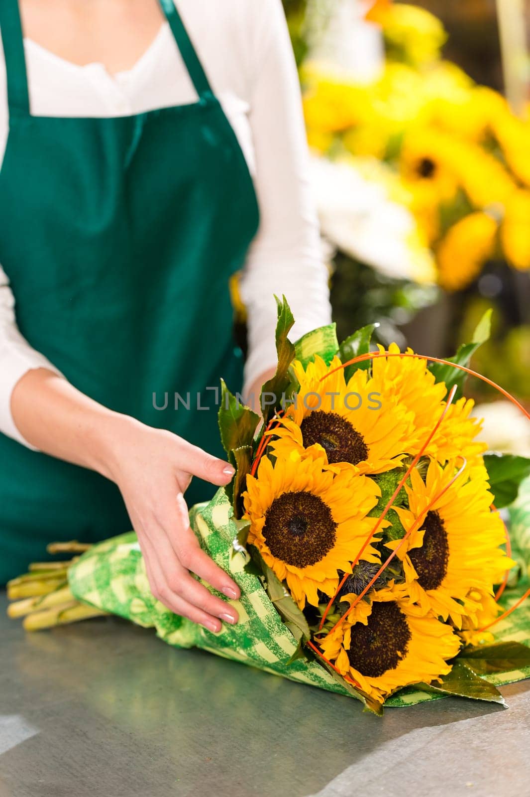 Florist preparing sunflowers bouquet flower shop assistant yellow hands