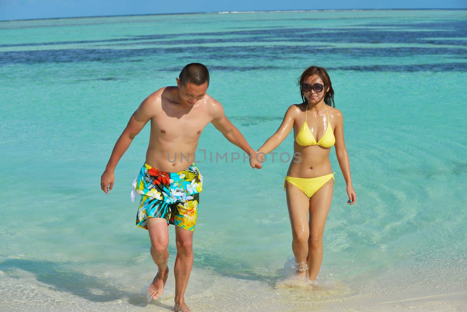happy young asian couple enjoying summer and have on beautiful white sand beach