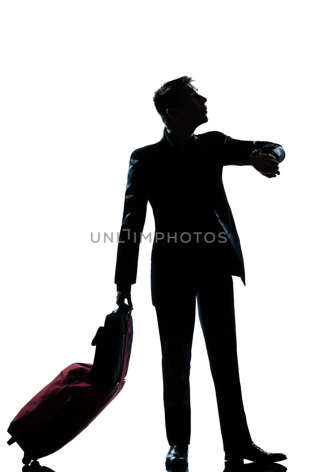 one caucasian  business traveler man checking the time full length silhouette in studio isolated on white background