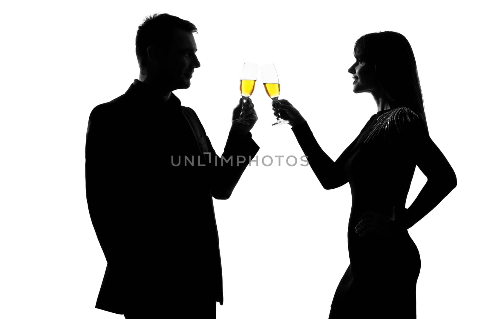 one caucasian couple man and woman drinking champagne toasting partying in studio silhouette isolated on white background