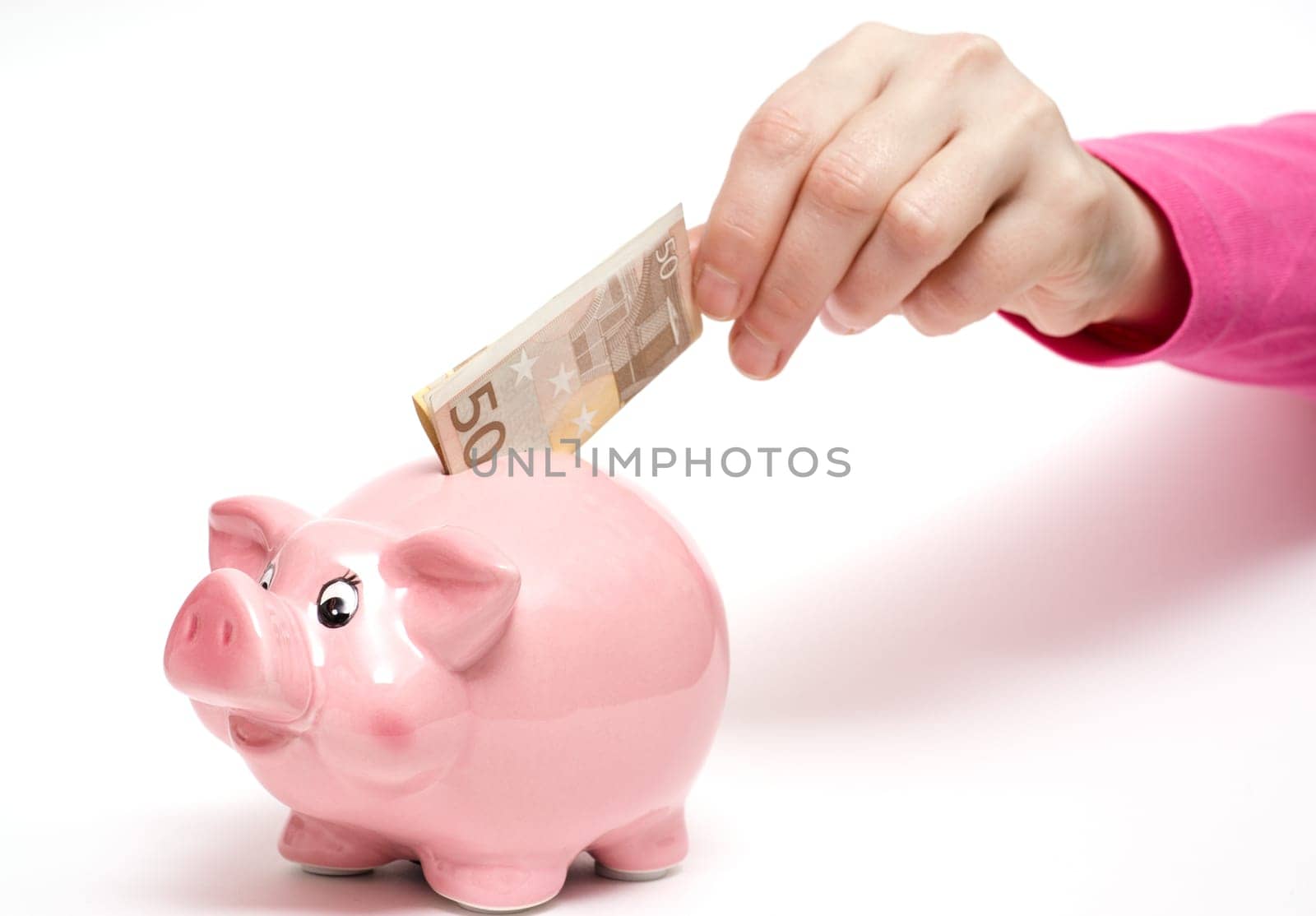 Pink piggy bank with 50 euro banknote in a female hand