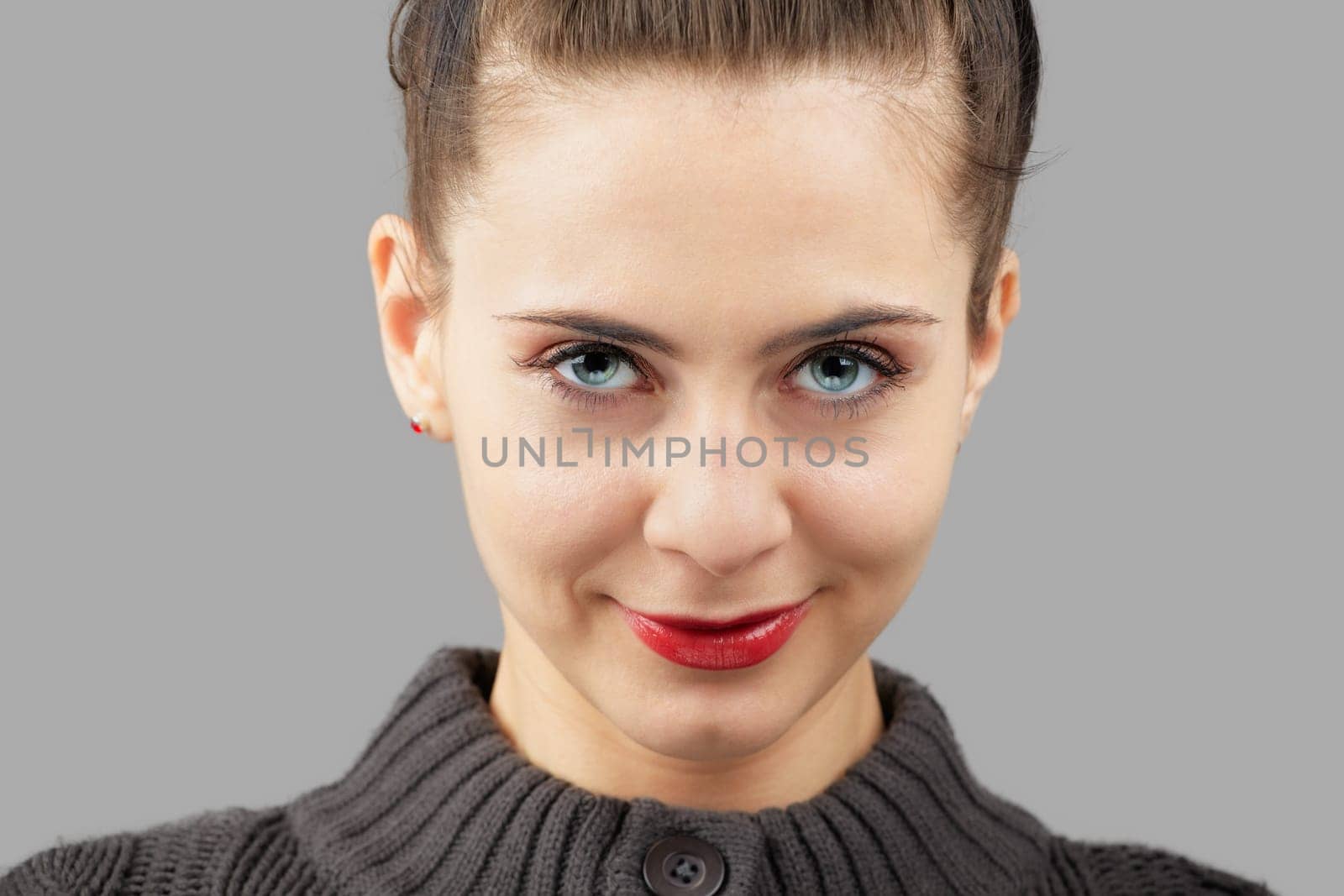 Portrait of a beautiful young woman with blue eyes isolated on grey