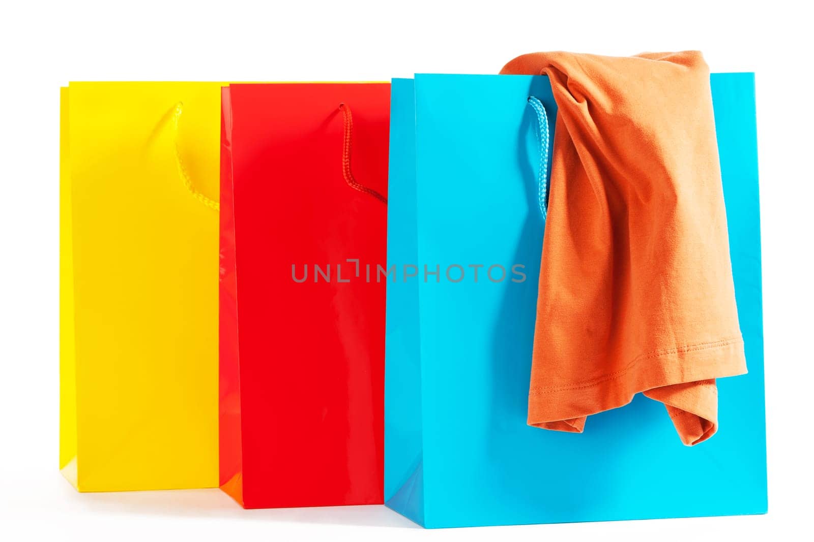 Three colorful shopping bags with shirt on white background